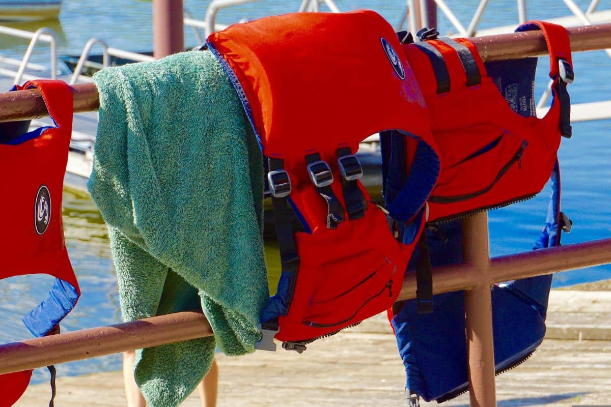 Personal flotation devices or life jackets hanging on a rack near the beach