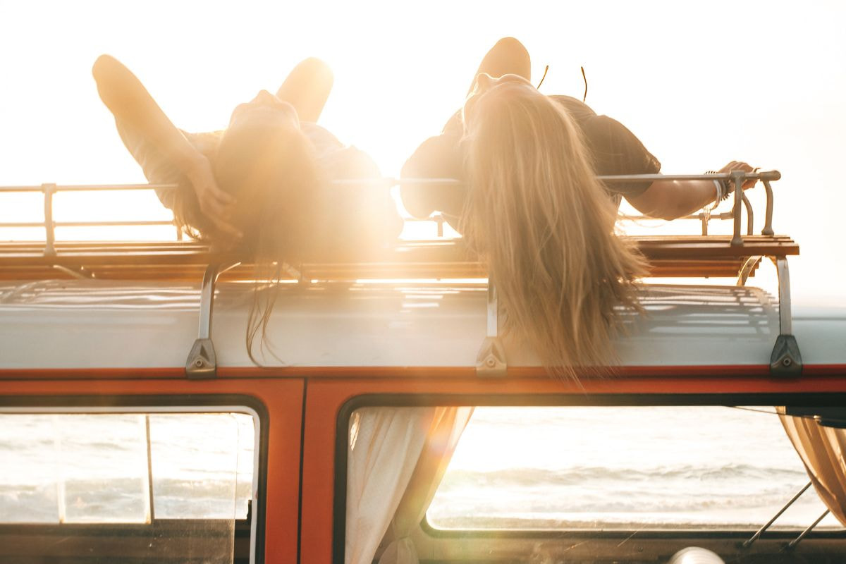 Two ladies lying on top of RV roof rails