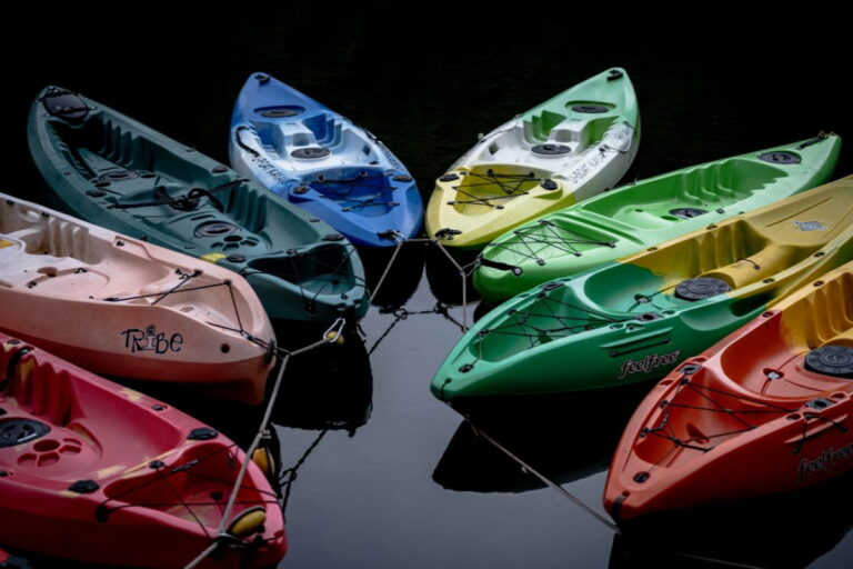 Eight kayaks on a dark background all facing the camera
