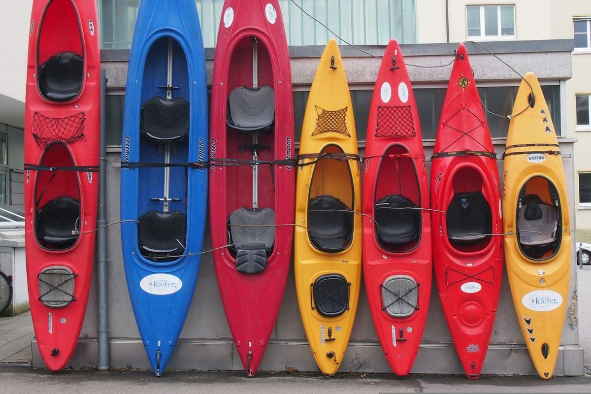 Seven kayaks of different sizes propped up vertically