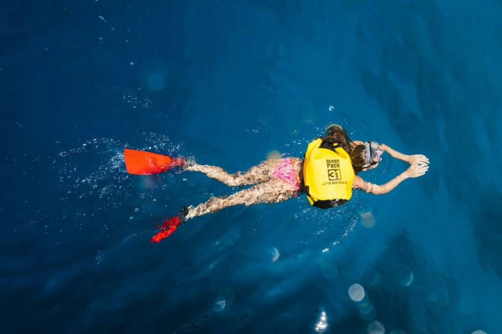 Woman swimming while carrying a dry bag on her back