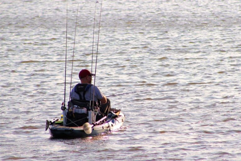 Man riding a kayak with modifications designed for fishing