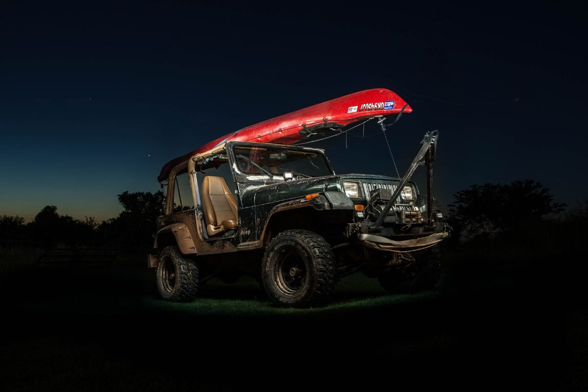 Red kayak strapped on top of an off-road vehicle