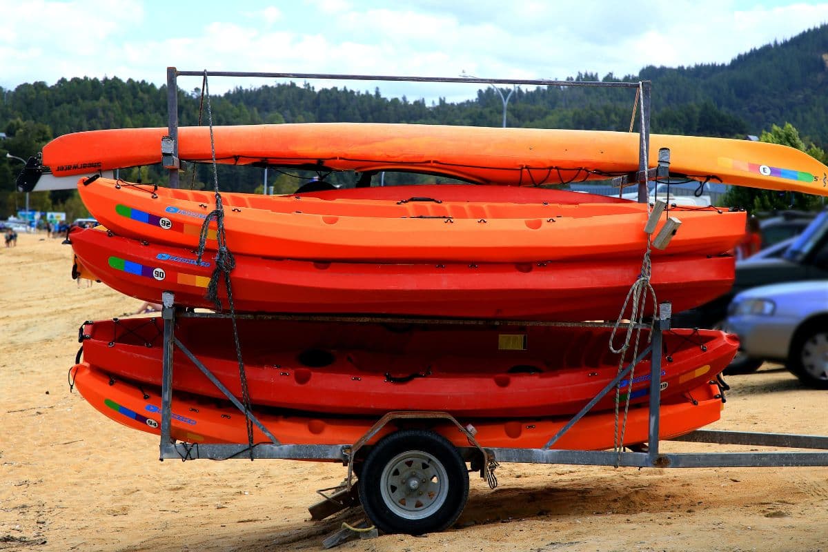 Five orange kayaks stacked up on a kayak trailer