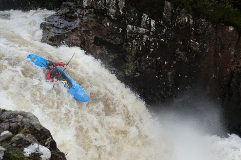 Person riding a kayak in very turbulent water rapids