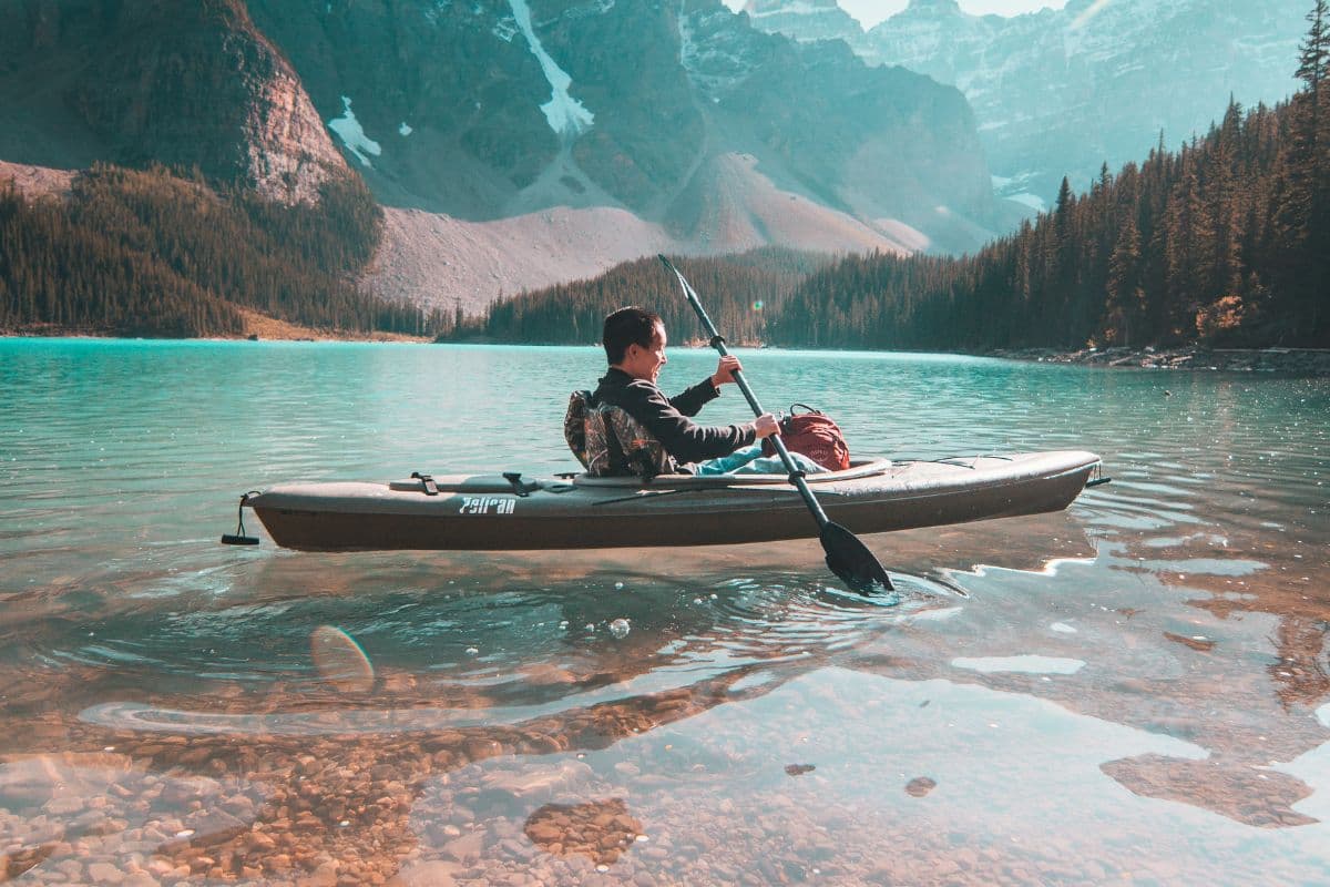 man paddling on a kayak in clear waters
