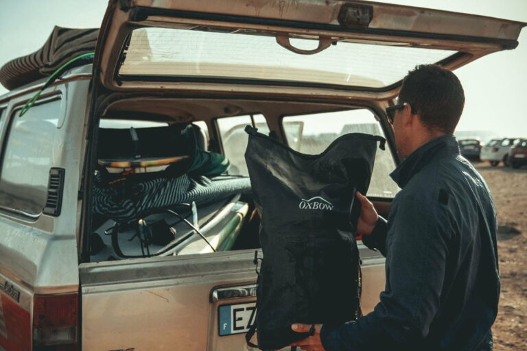 Man loading a dry bag in the back of a car
