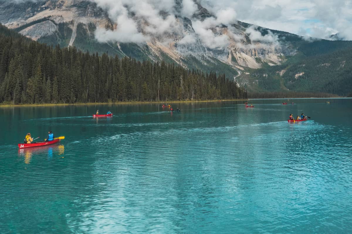 Multiple people riding on canoes and kayaks on a lake
