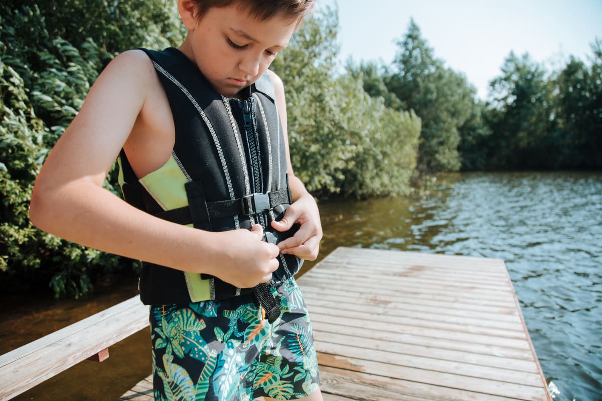 Boy putting on a life jacket or personal flotation device