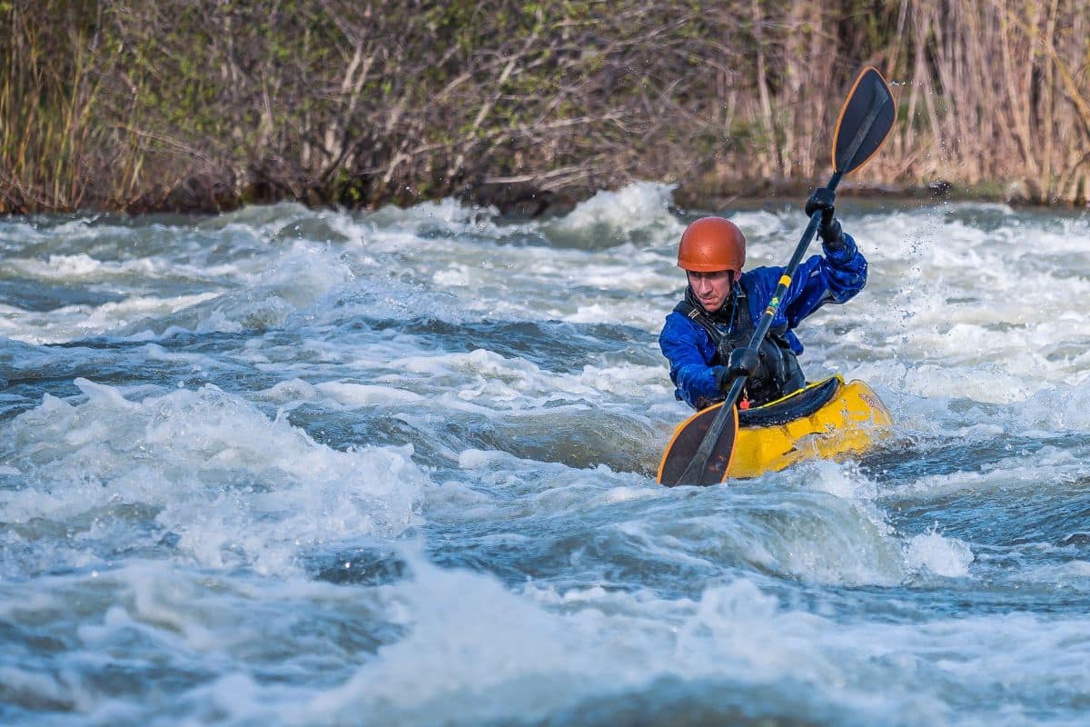 Man riding a river runner kayak in whitewater rapids