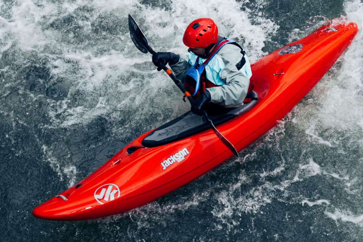 Person riding a red kayak in water with strong currents