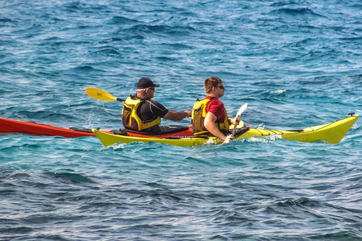 Two people riding kayaks at sea