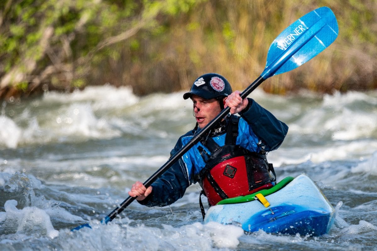 Man riding a kayak in a river with strong currents