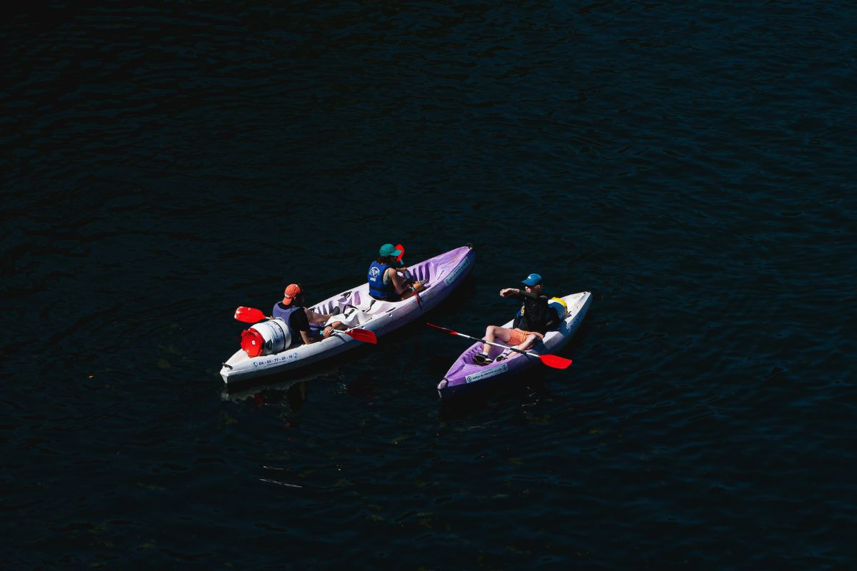 People riding on a tandem kayak and a single kayak in the middle of a lake