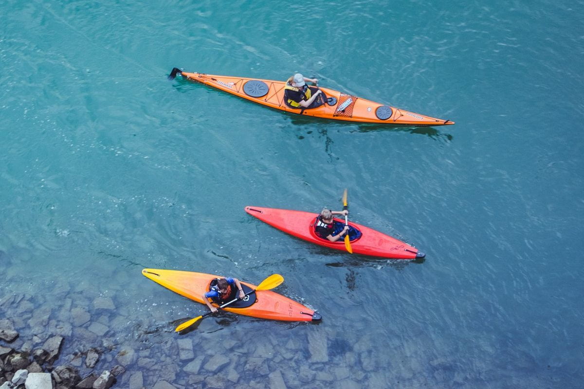 Three people riding one touring kayak and two recreational kayaks