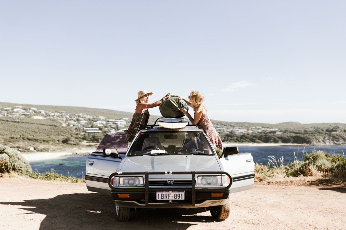 Two people on top of a car loading luggage