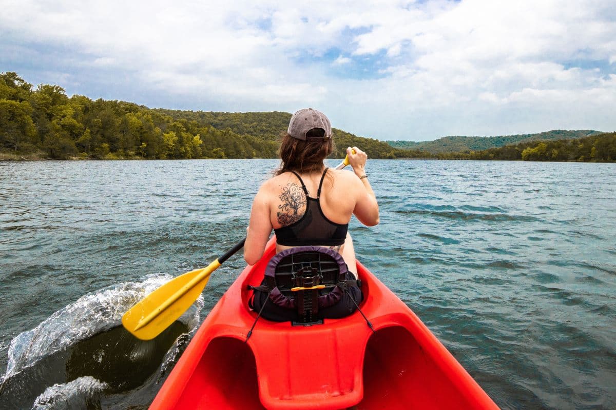 Woman paddling on kayak shown from the back